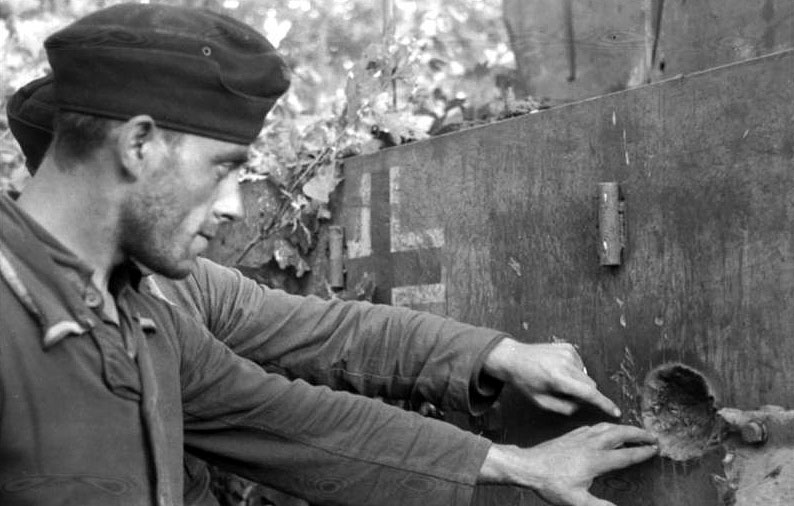 Двое германских военнослужащих осматривают выбоину от попадания снаряда в бортовую броню корпуса «Тигра»
